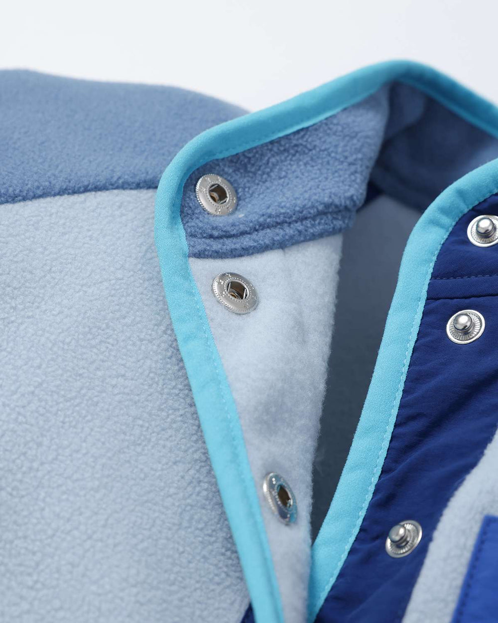 Lightweight fleece jacket collar detail with snap buttons and light blue contrast trim