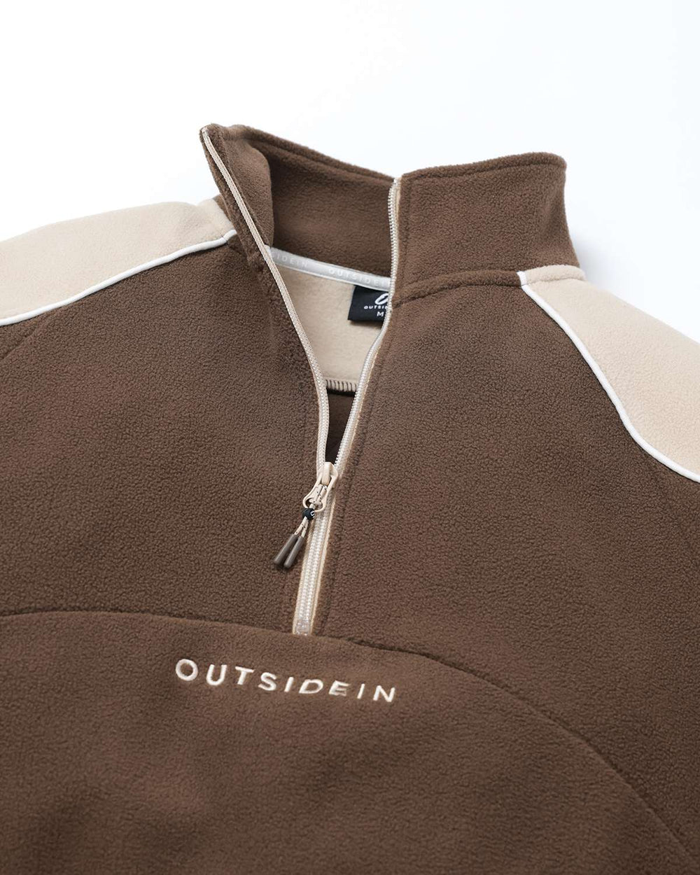 Brown half-zip fleece with cream shoulder panels, stand collar, and zipper pull