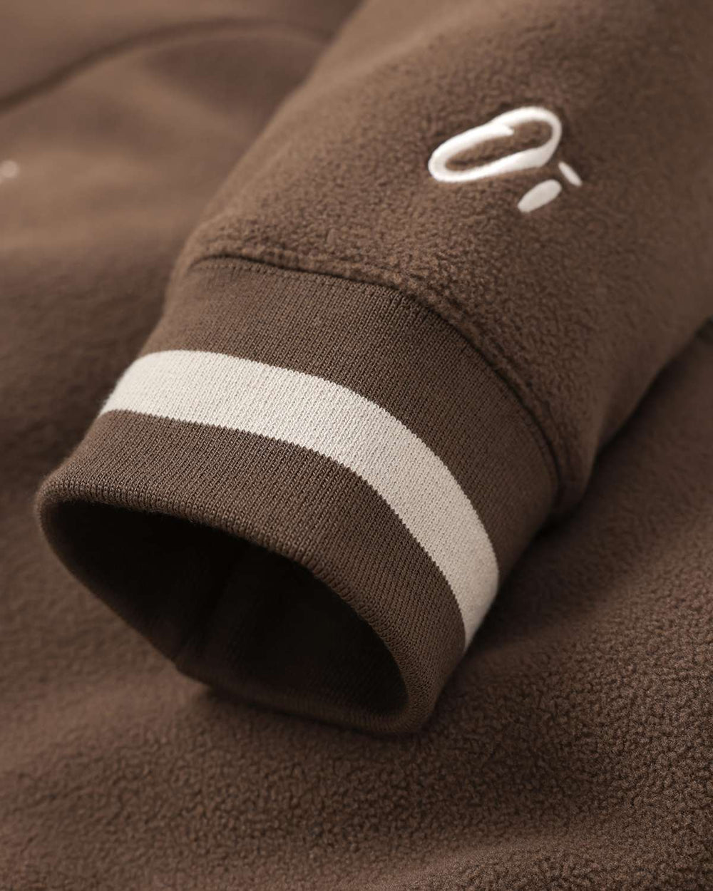 Brown fleece cuff with two-tone ribbing and stitched logo on the sleeve