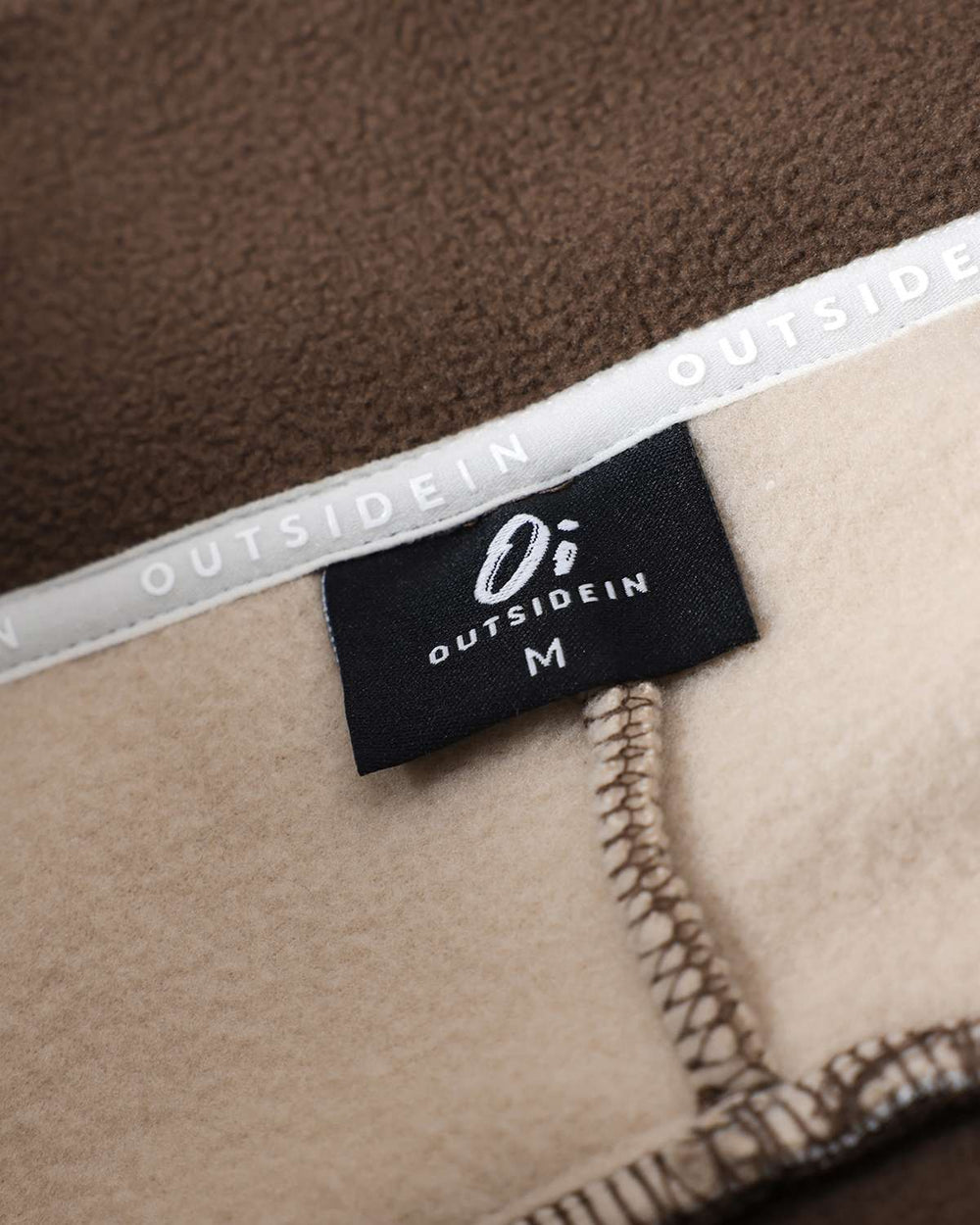Brown fleece neck label with OutsideIn branding and inner seam stitching