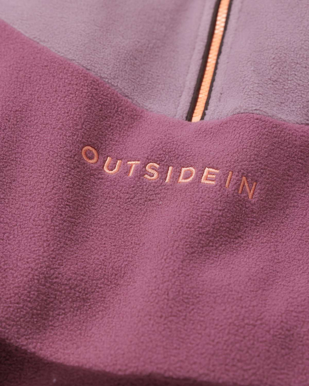 OutsideIn logo on mauve fleece panel with quarter-zip opening and orange-gold zipper