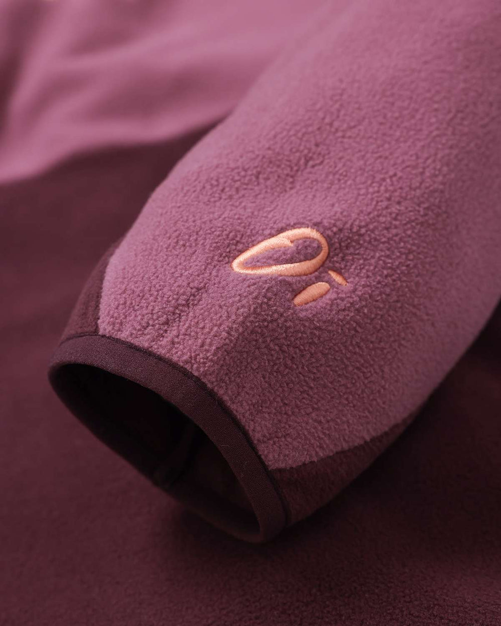 Fleece sleeve cuff with OutsideIn logo embroidery on burgundy fabric