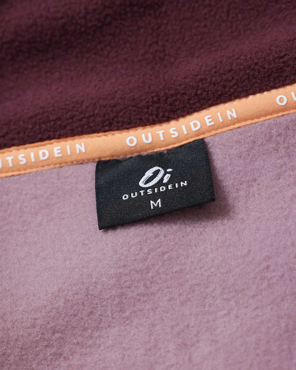 Inside neckline brand label on burgundy fleece with orange-gold edge trim