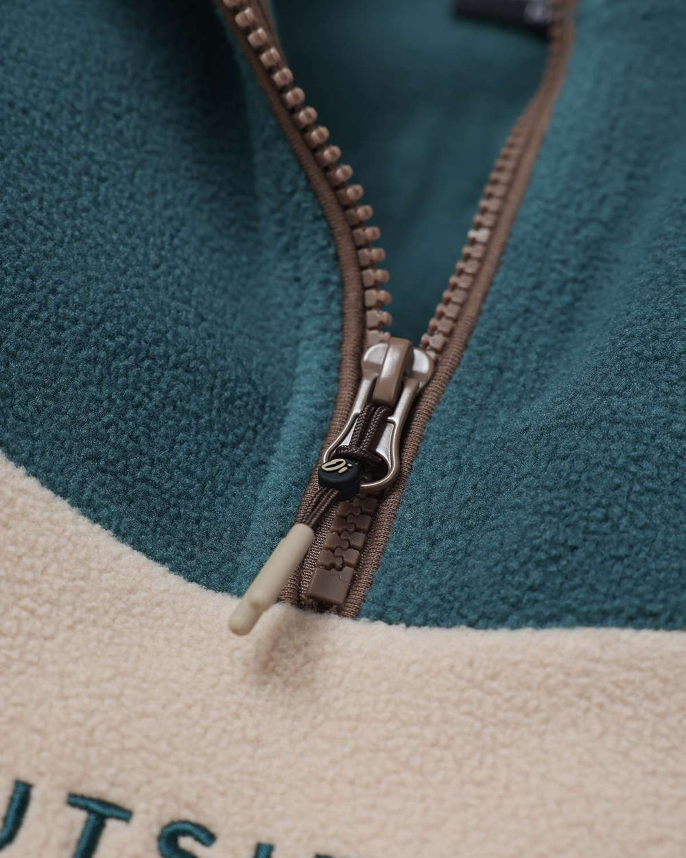 Fleece quarter-zip with brown zipper and toggle pull; teal and cream color blocks