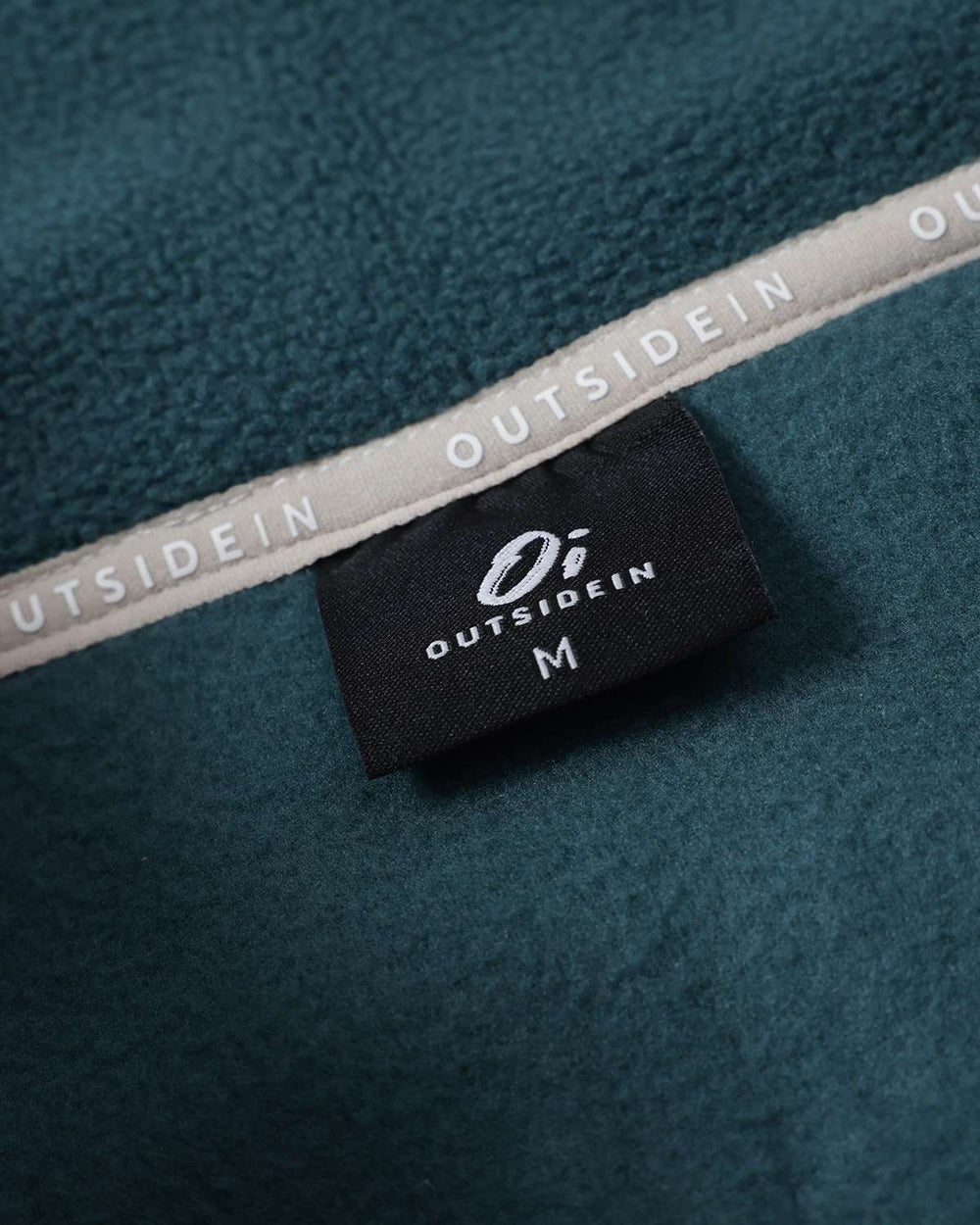 Inside neck label on teal fleece with OutsideIn branding 
