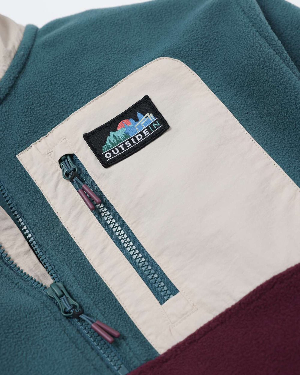 Teal microfleece jacket with white interior panel and branded patch near the zipper