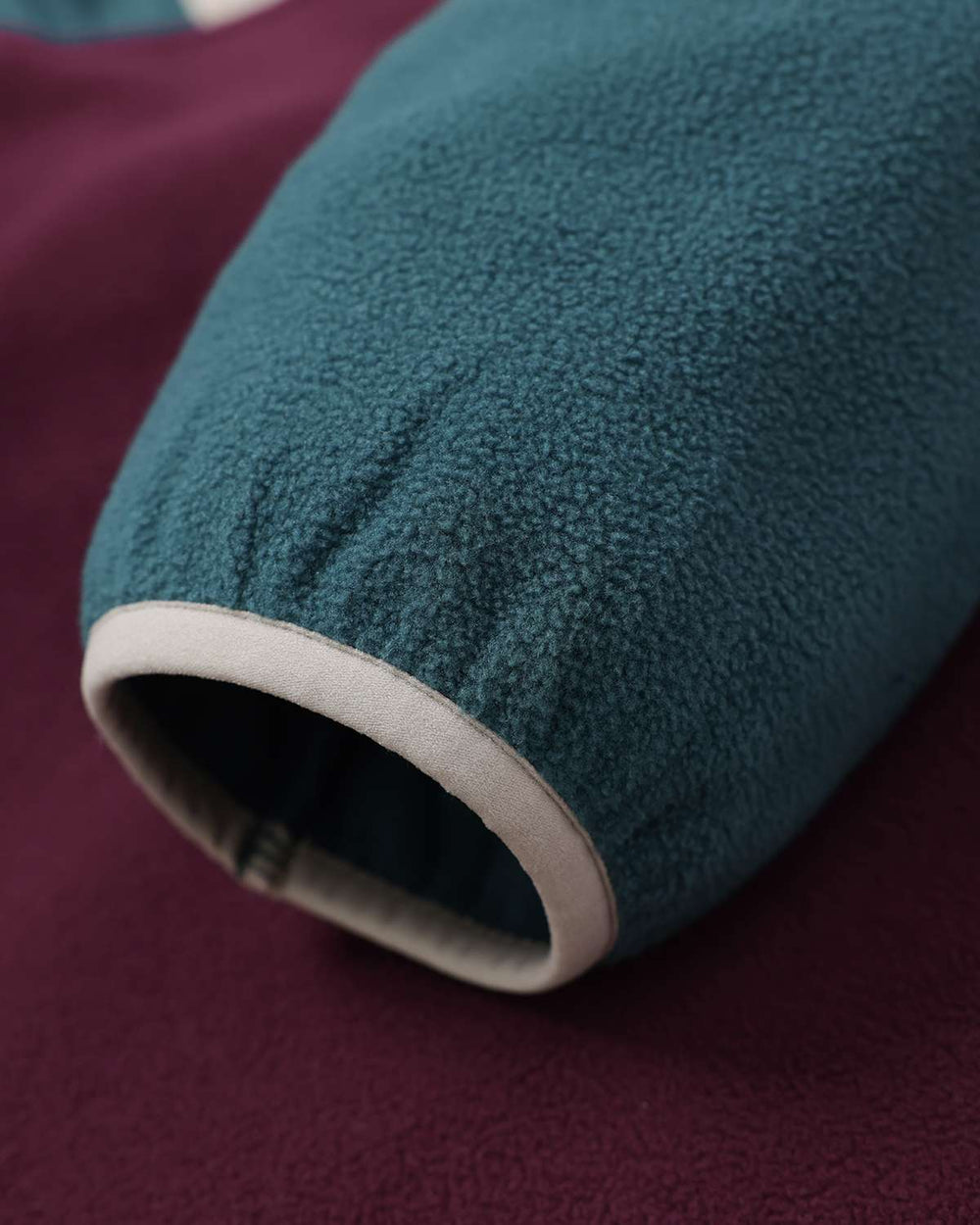 Fleece jacket sleeve cuff in teal with contrast trim on maroon lower body