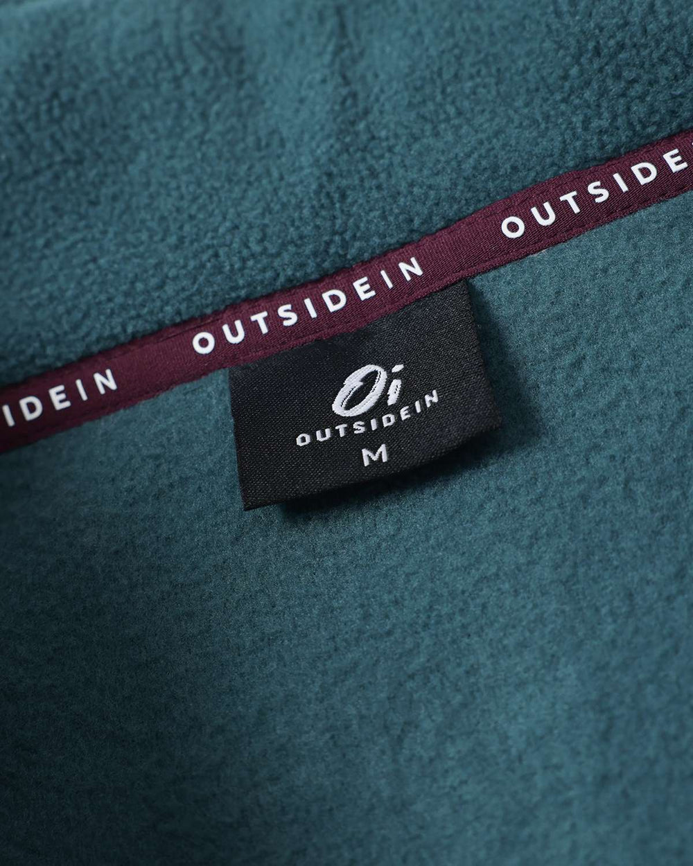 Neckline interior trim with brand print label on teal microfleece jacket