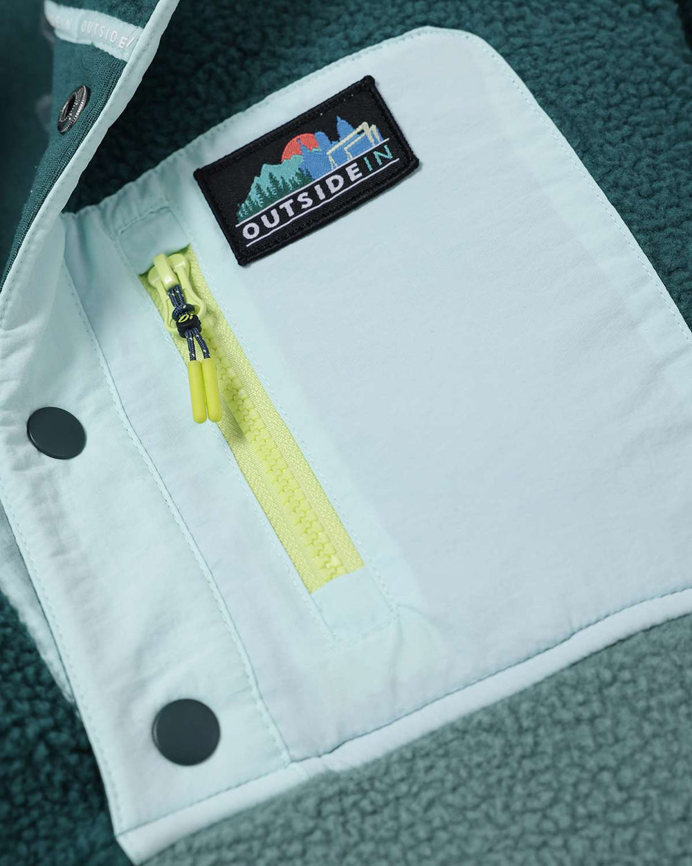 Evergreen fleece button-up with white placket, black logo patch, and zipper pocket