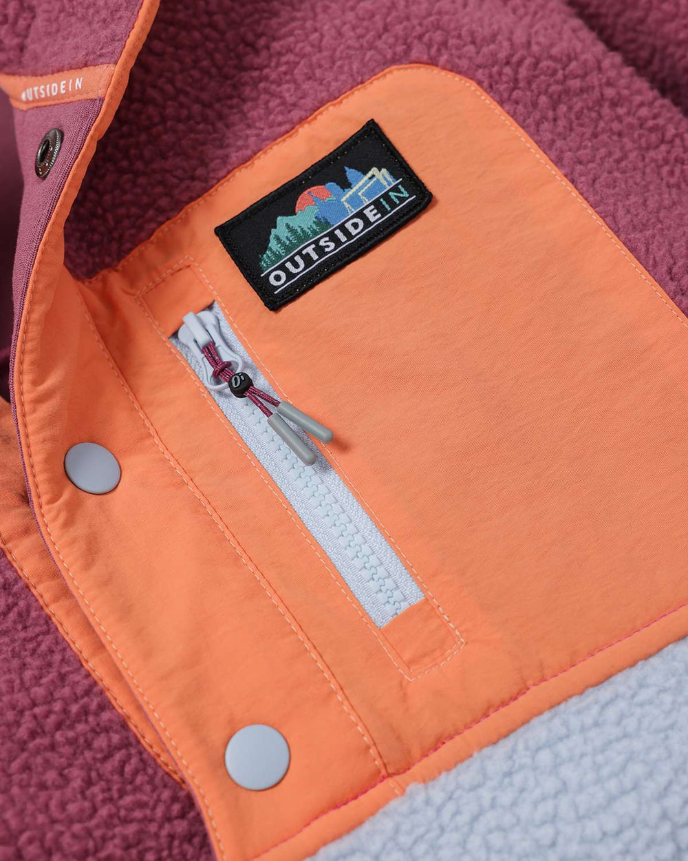 Sherpa fleece jacket front panel with orange overlay, snap buttons, and chest patch.