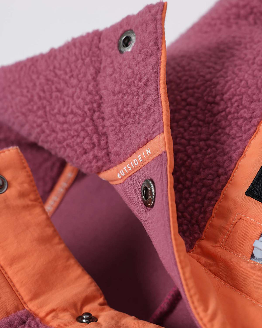 Purple fleece button placket and stand collar with orange trim and snap fasteners.
