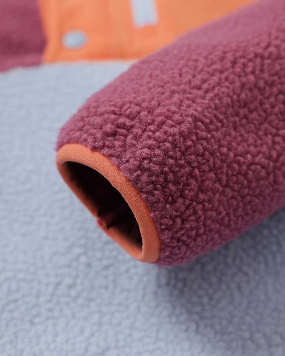 Cuffed fleece sleeve end in purple with light blue body and open hem lining.