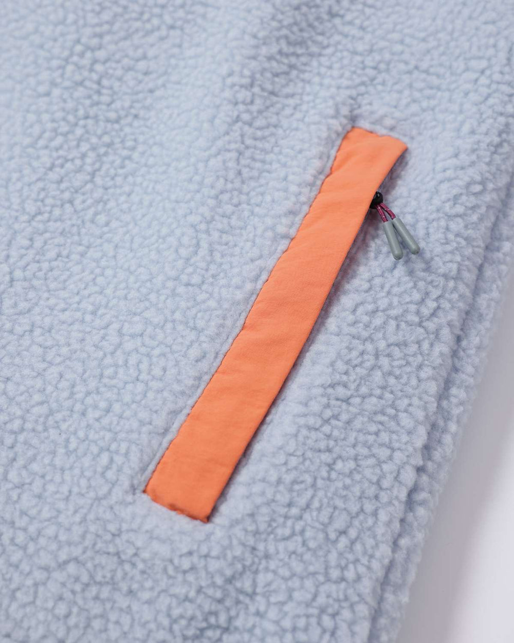 Light blue fleece body with an orange side tab and small zipper pull detail.
