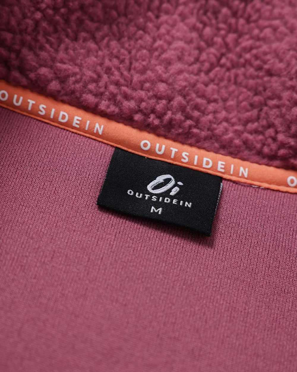 Purple fleece inner neck label area with OutsideIn branding and size tag.