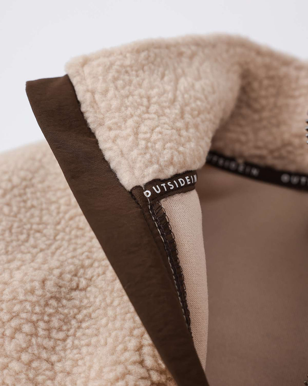 Fleece full-zip jacket collar detail with OutsideIn logo patch and brown trim