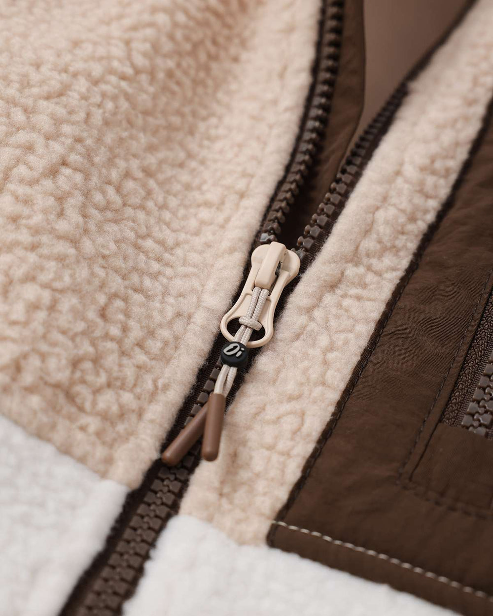 Fleece full-zip jacket zipper detail with dark brown trim and metal pull tab