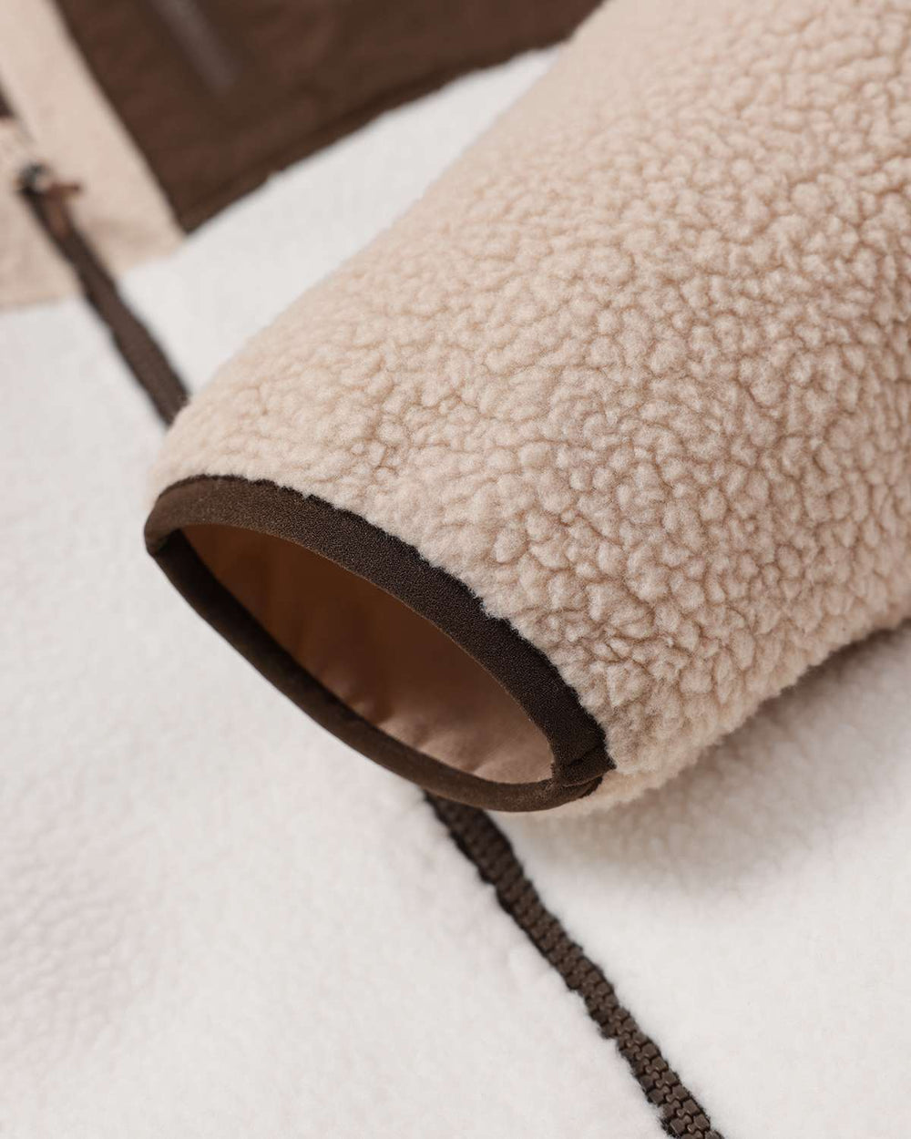 Fleece full-zip jacket hem and sleeve opening with brown binding and zipper stitch line