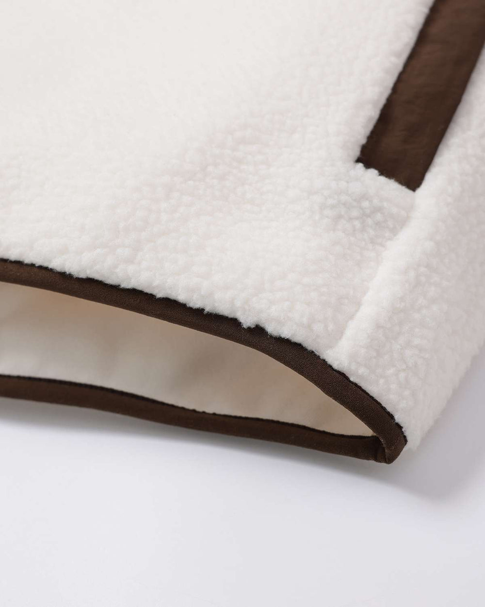 Fleece full-zip jacket hem corner with brown edging and stitched seam
