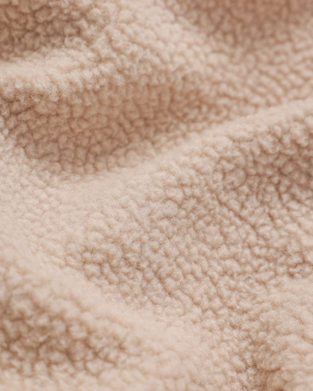 Beige borg fleece fabric close-up with textured sherpa-like pile surface