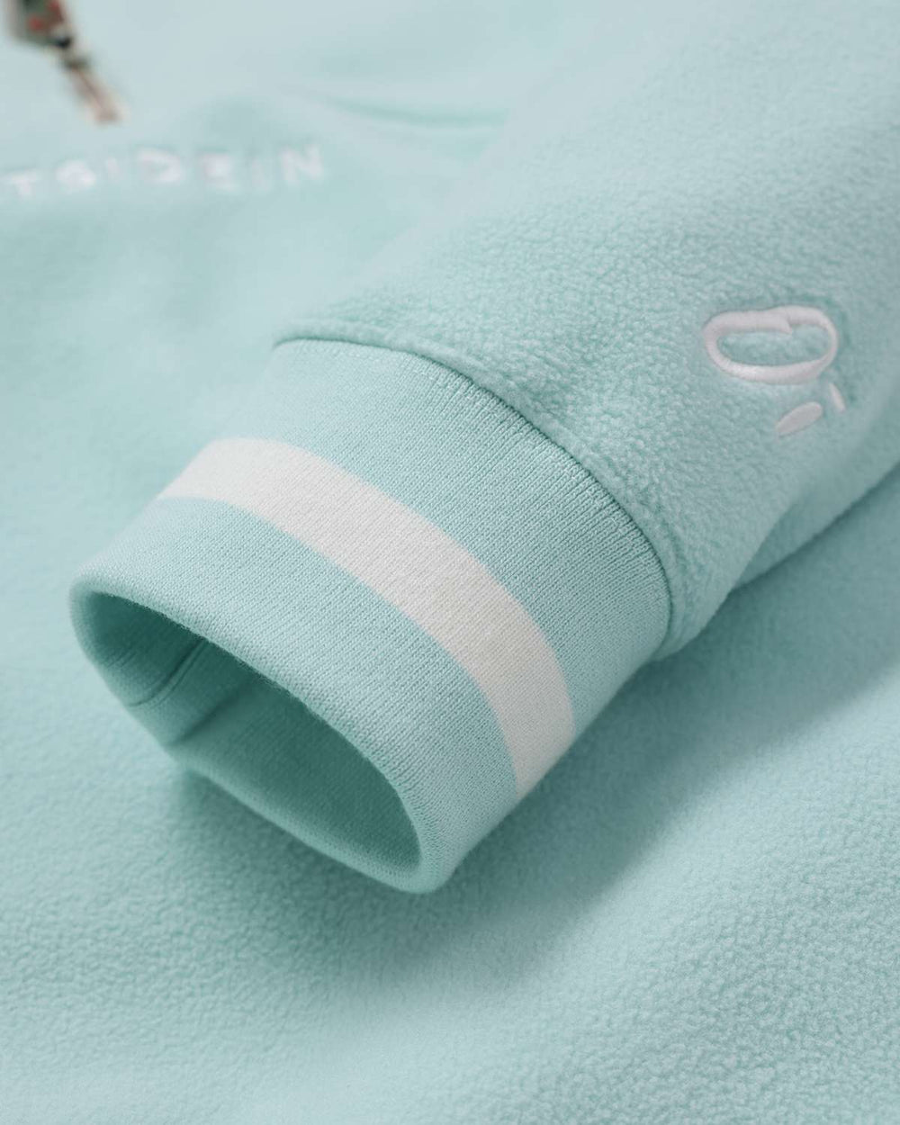 Light teal fleece sleeve with ribbed cuff and light stripe detail at the hem