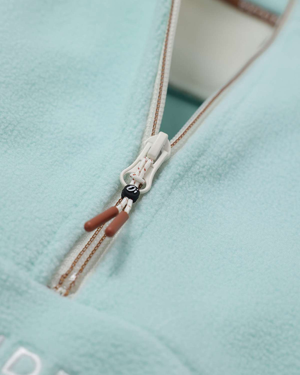Light teal fleece quarter-zip with zipper pull and brown-and-white cord tassel