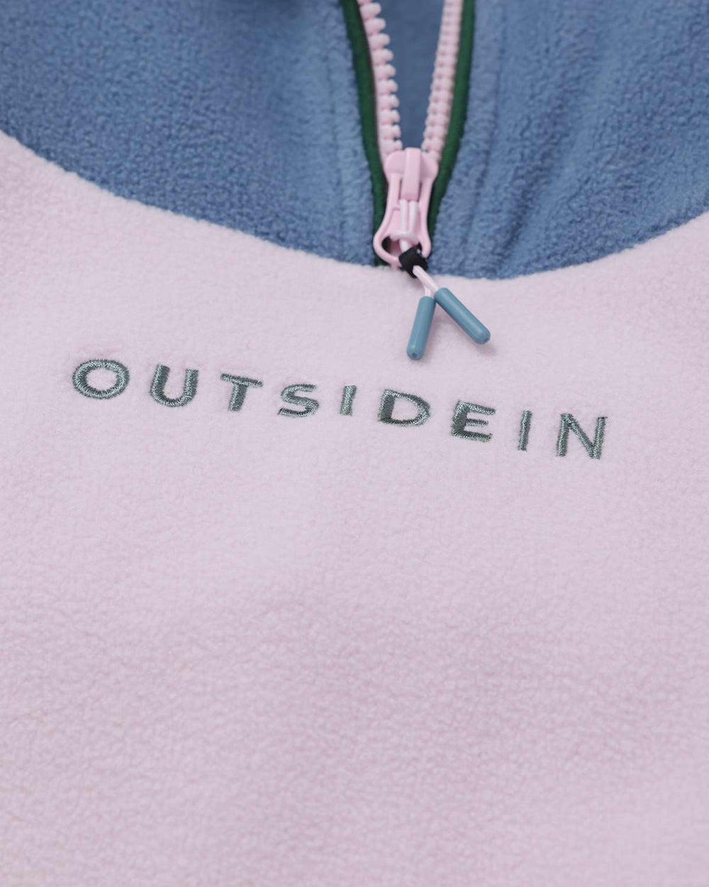 Fleece quarter-zip close-up with pink zipper pull and embroidered logo on chest