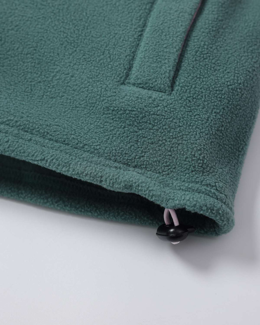 Green fleece hem with stitched pocket seam and small black button at bottom