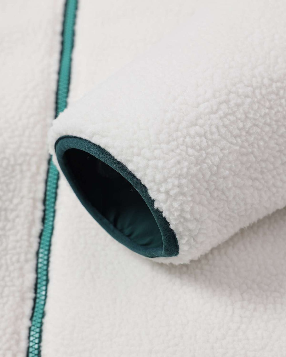 White sherpa fleece jacket with dark teal lined opening near zipper