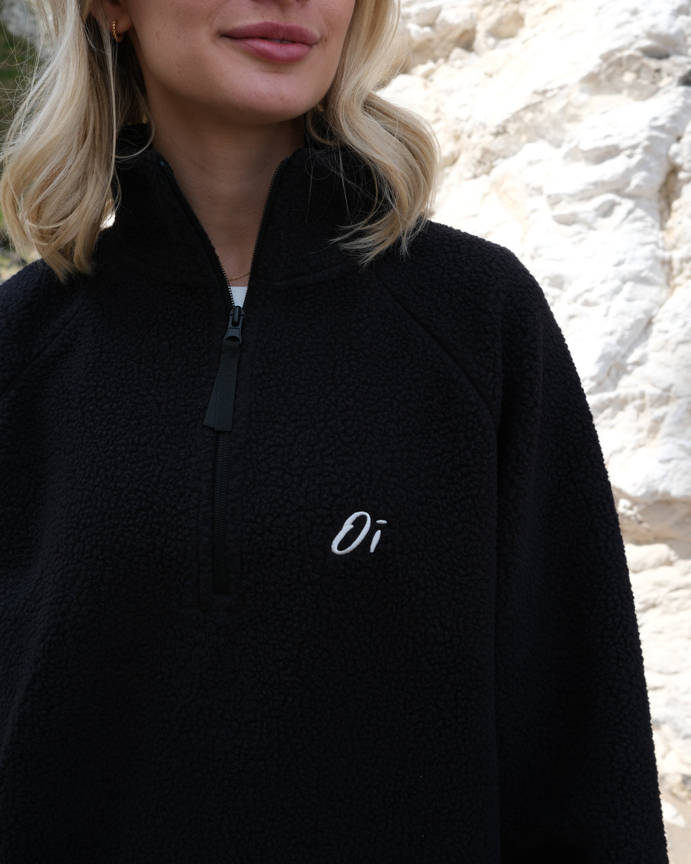 Close up of Model wearing OutsideIn Black Teddy Quarter Zip Fleece logo