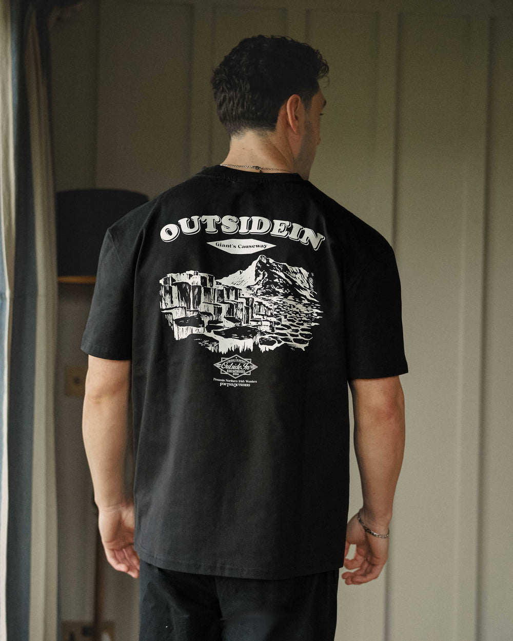 Model wearing a black t-shirt with OutsideIn graphic design on the back.