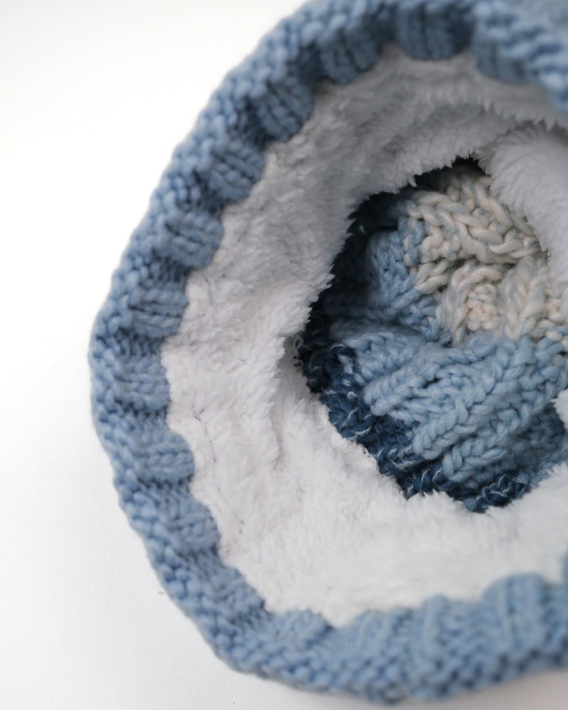 Pom hat with Arctic Breeze blue hues, cable knit design, and soft fleece-lined base