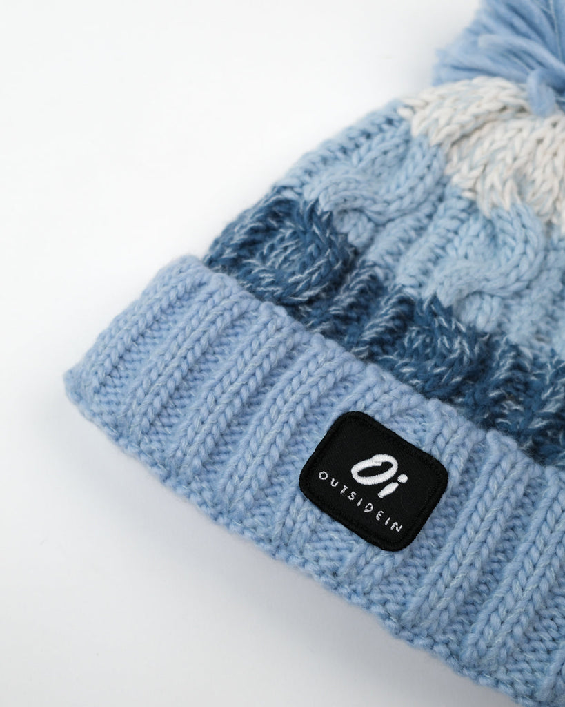 Pom hat with Arctic Breeze blue hues, cable knit design, and soft fleece-lined base