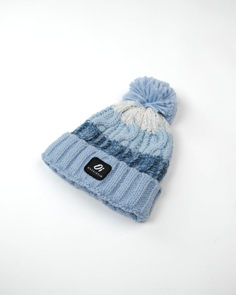 Pom hat with Arctic Breeze blue hues, cable knit design, and soft fleece-lined base