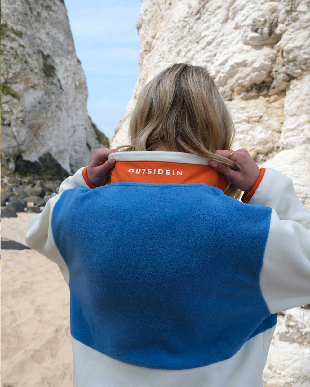 Model wearing Outside Blue & Orange Signature Pocket Fleece showing neck branding