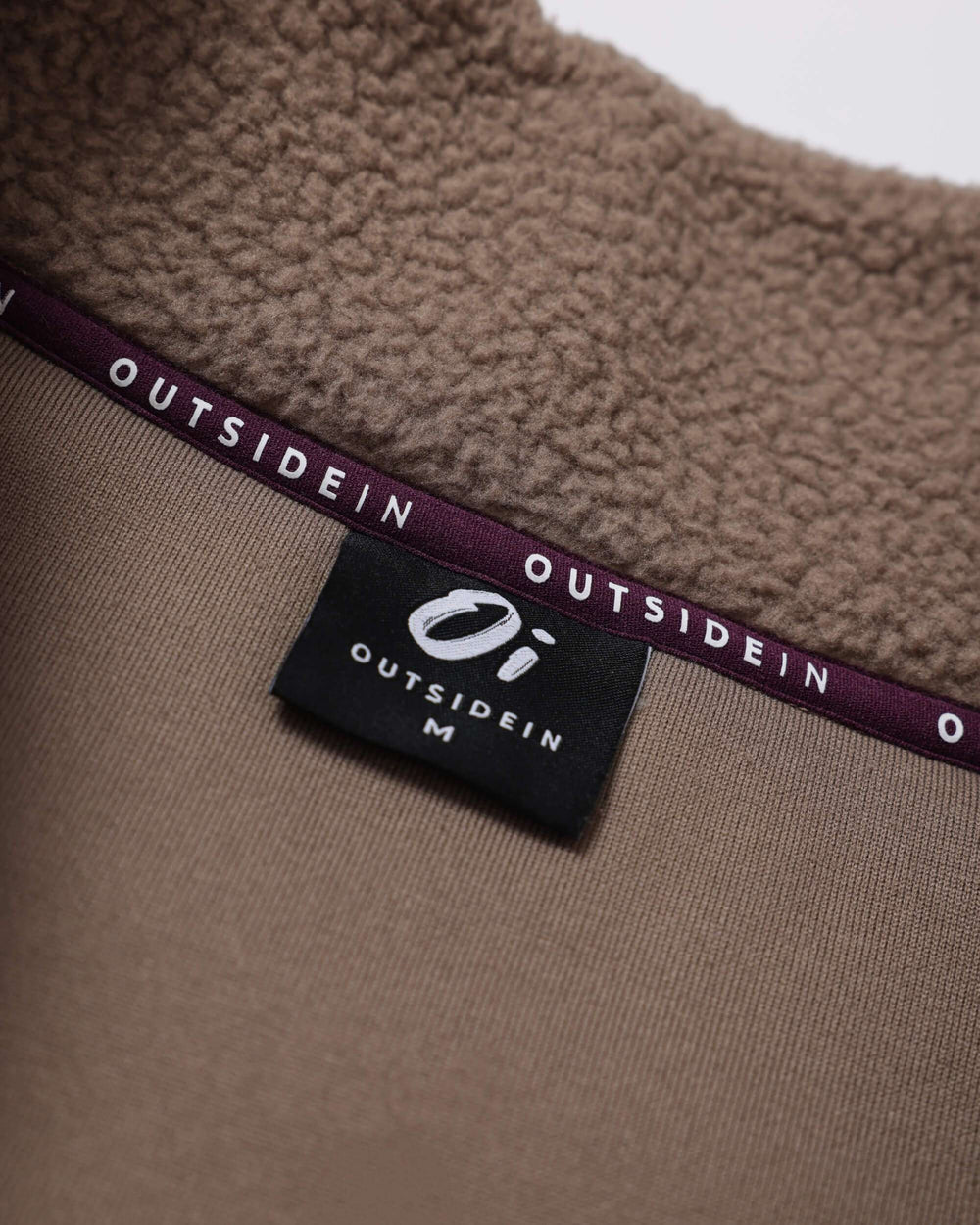 OUTSIDEIN brand label on borg fleece collar, brown fabric with purple trim