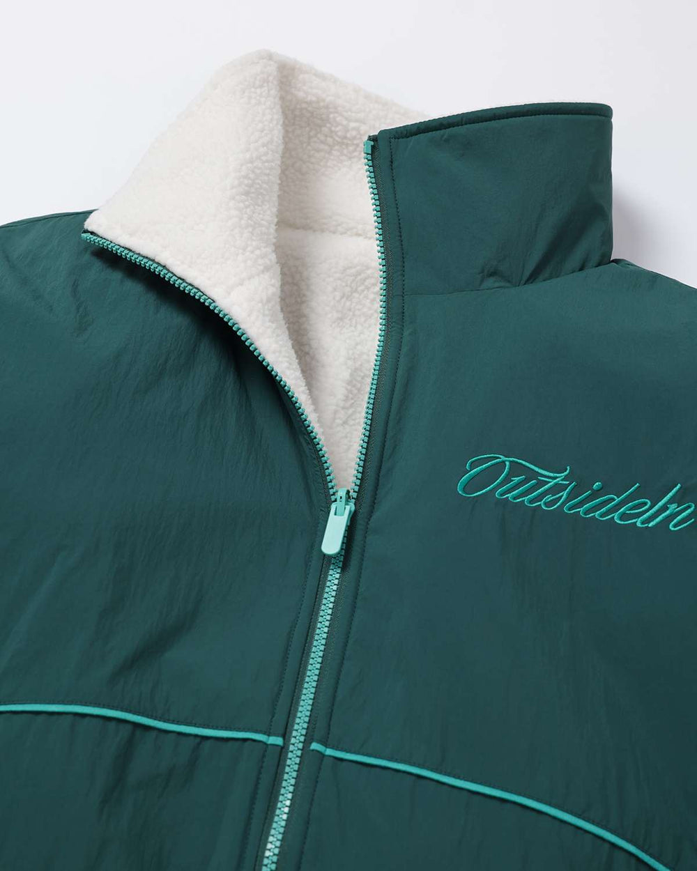 Dark teal fleece jacket close-up with embroidered logo and high collar zipper