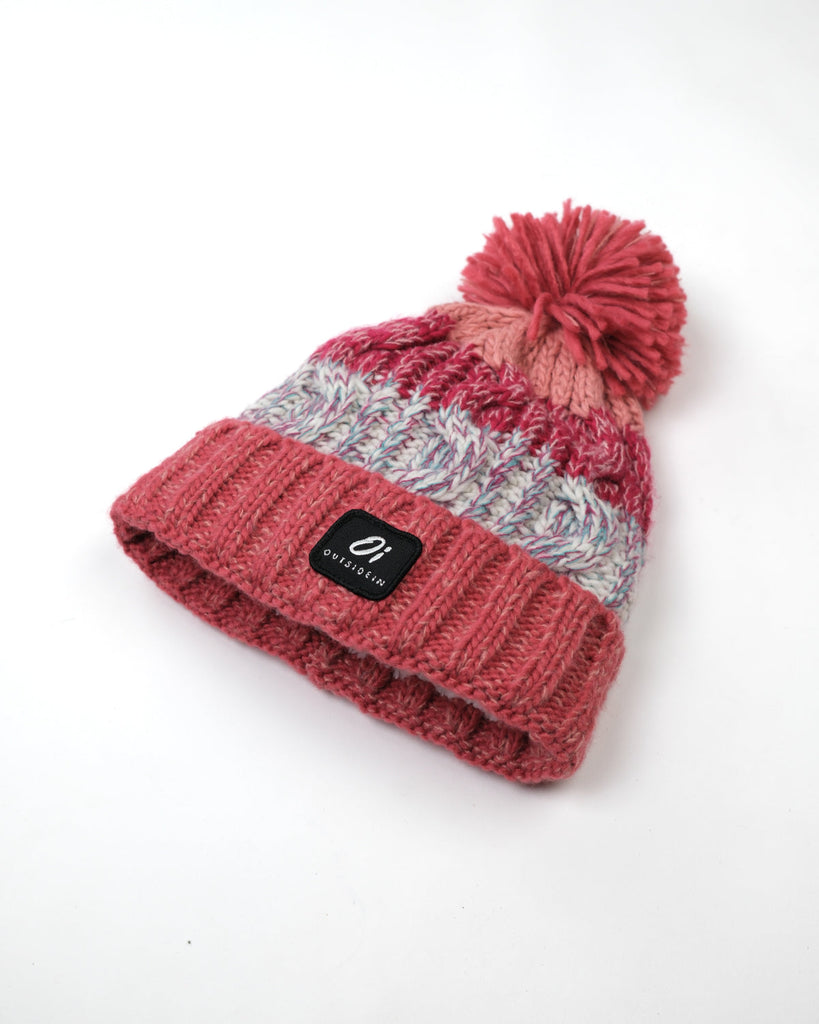 Pom hat in Coral Reef colour with classic cable knit pattern and partial fleece base lining