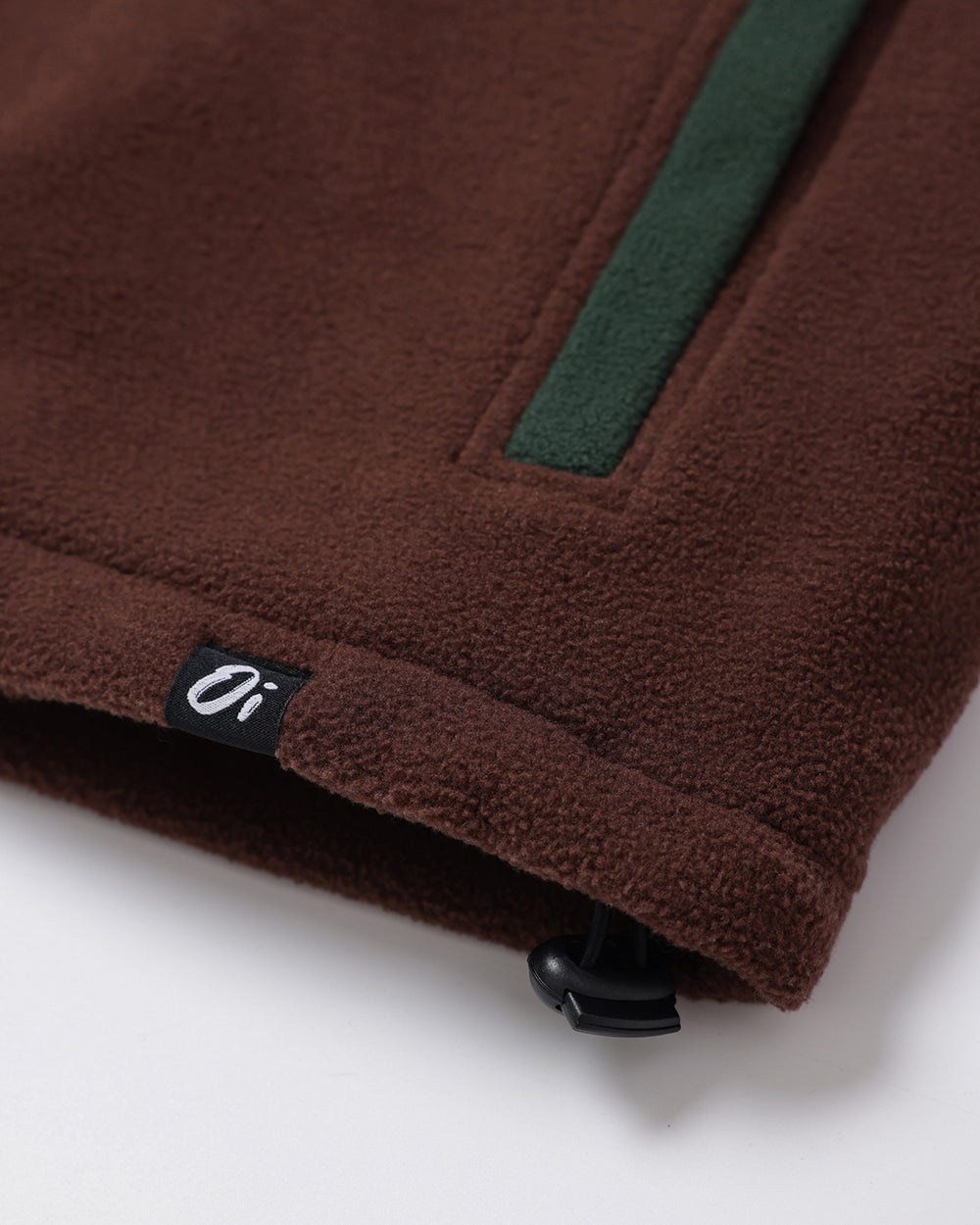 Close-up of Green Brown Signature Pocket Fleece Flat lay label on flat lay.