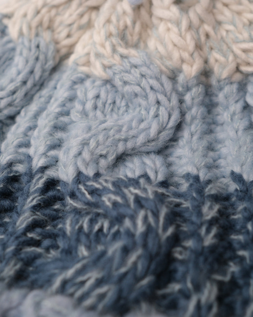 Pom hat with Arctic Breeze blue hues, cable knit design, and soft fleece-lined base