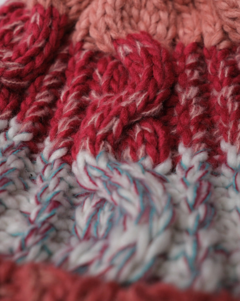 Pom hat in Coral Reef colour with classic cable knit pattern and partial fleece base lining