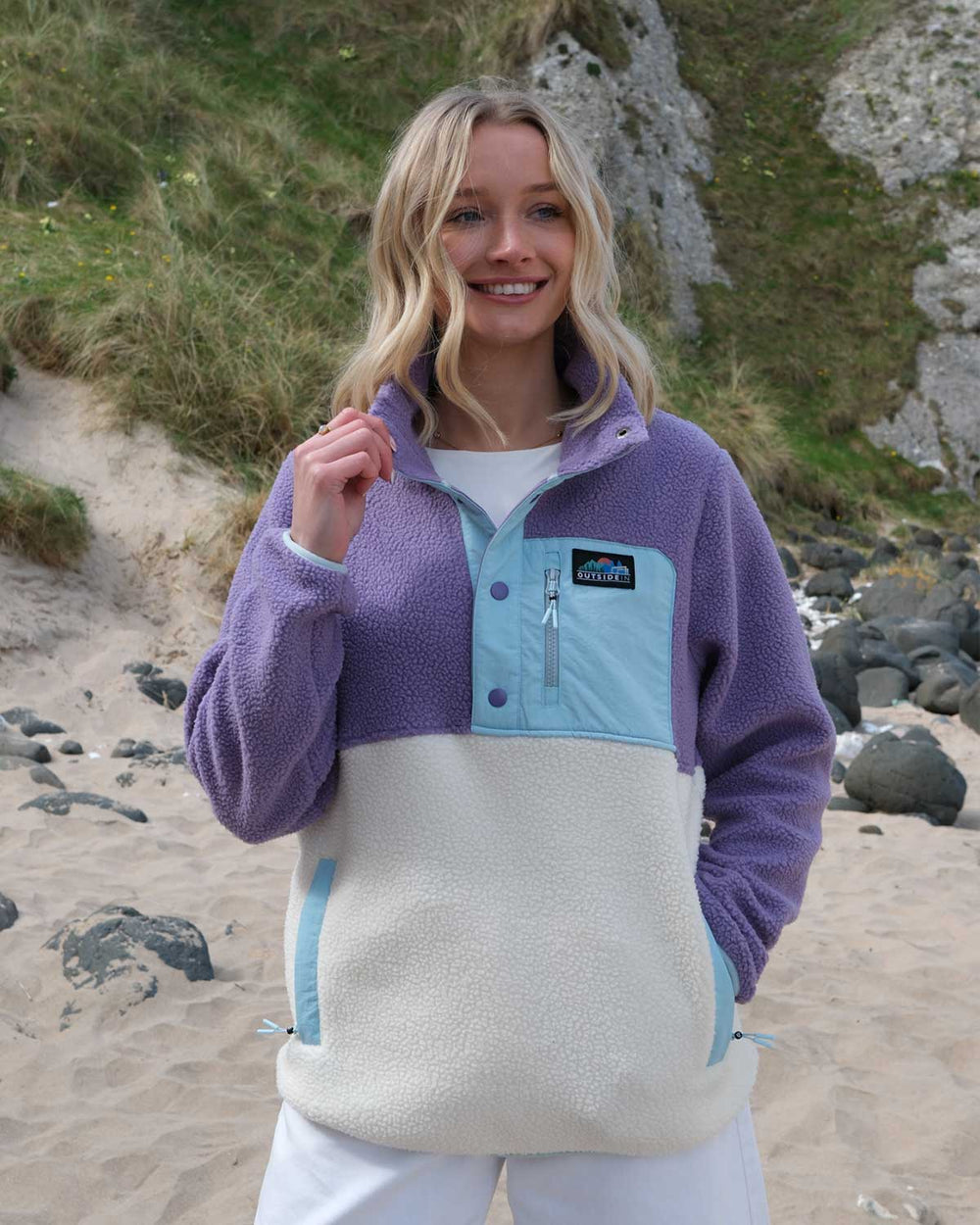 Model wearing an OutsideIn Meadow Button Up Borg Fleece with on a beach.