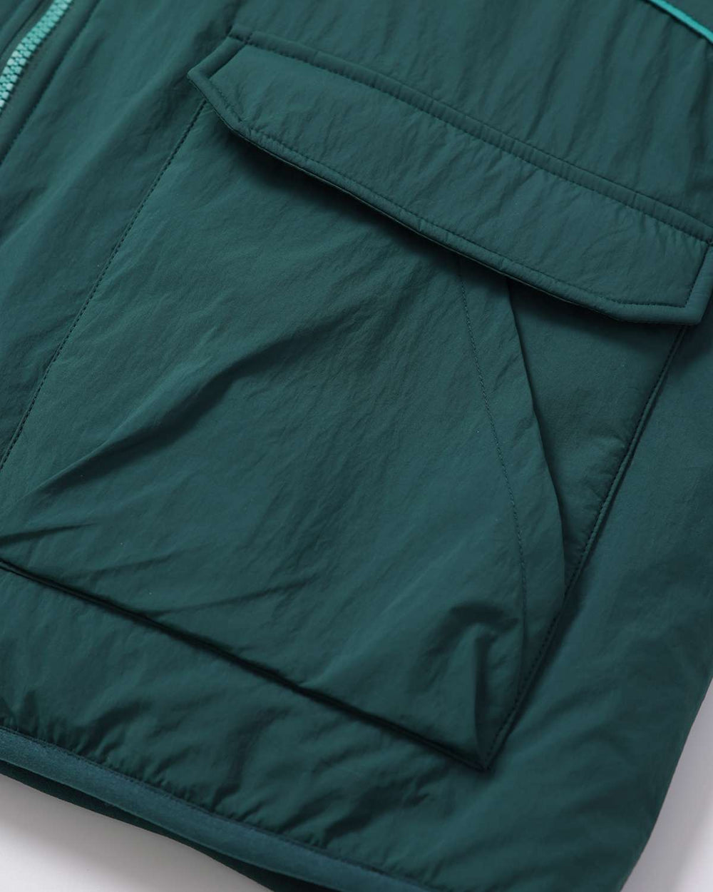 Dark teal jacket front with flap pockets and curved contrast piping