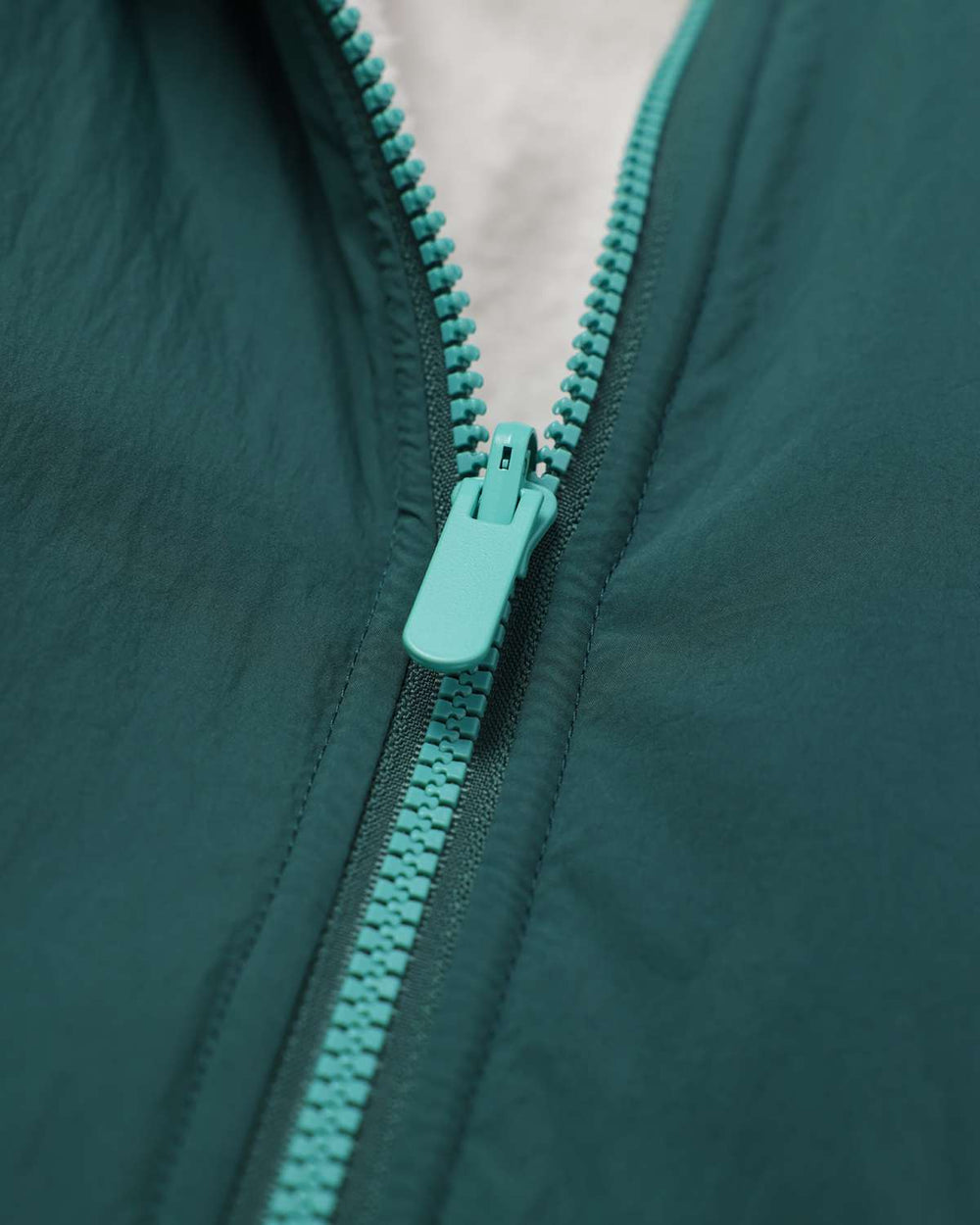Dark teal jacket detail with turquoise zipper and pull tab