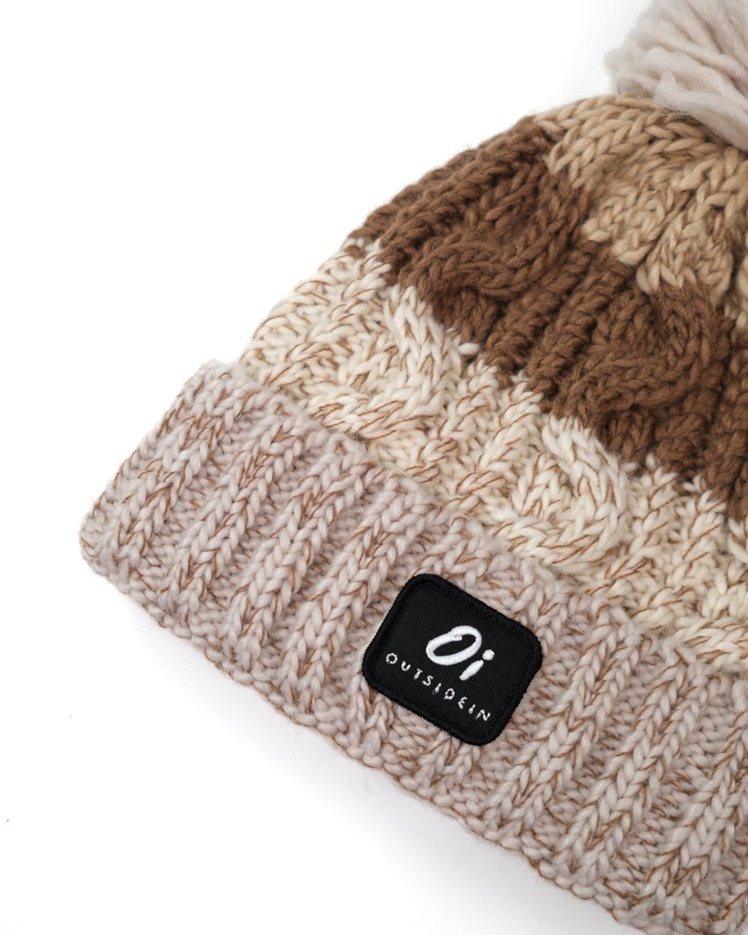 Pom hat in hazelnut swirl colour with classic cable knit pattern and partial fleece base lining
