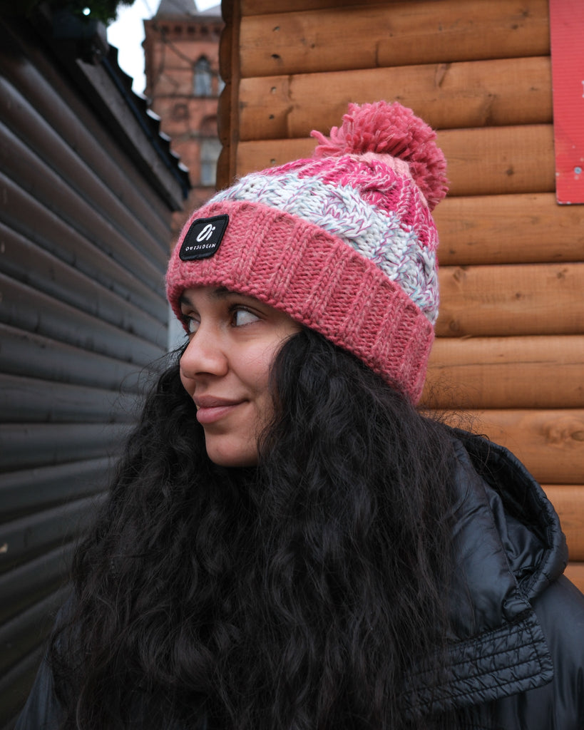 Pom hat in Coral Reef colour with classic cable knit pattern and partial fleece base lining