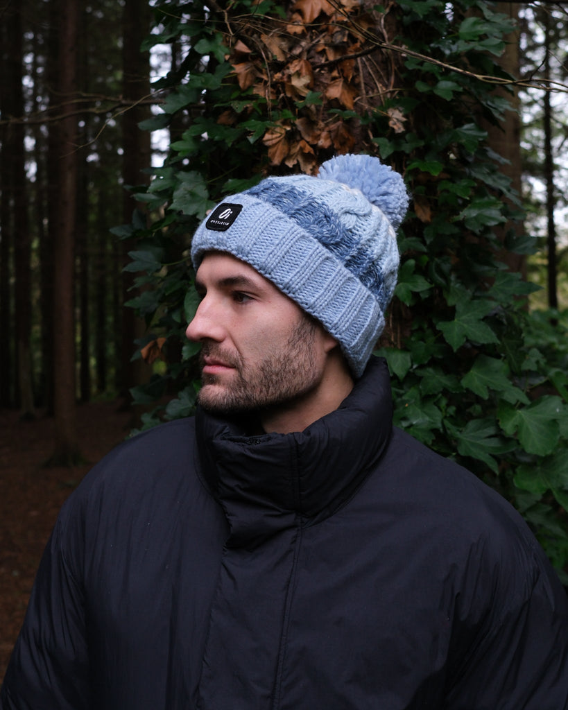Pom hat with Arctic Breeze blue hues, cable knit design, and soft fleece-lined base