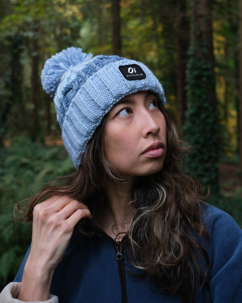 Pom hat with Arctic Breeze blue hues, cable knit design, and soft fleece-lined base