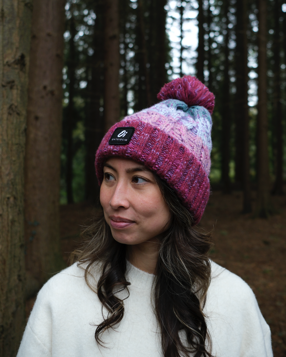 Maroon and pastel knit beanie with pom pom, worn on head