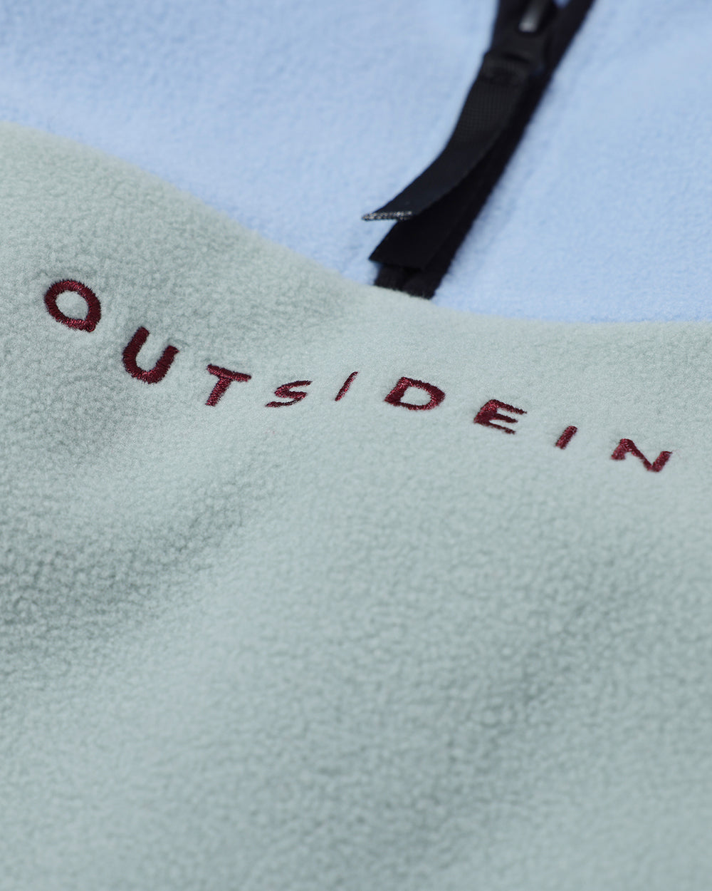 OutsideIn Text 'OUTSIDEIN' embroidered on a light blue fleece jacket.